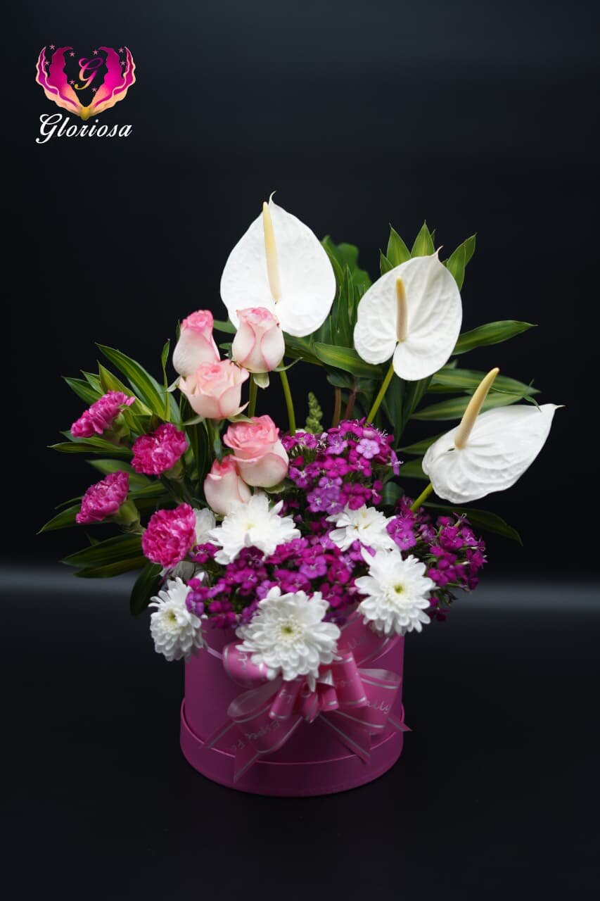 White anthurium with purple flowers in pink ribbon box